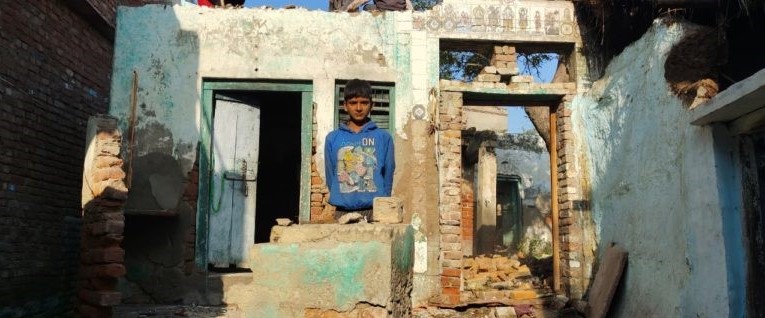 Dani Sharma standing amidst the rubble of his house